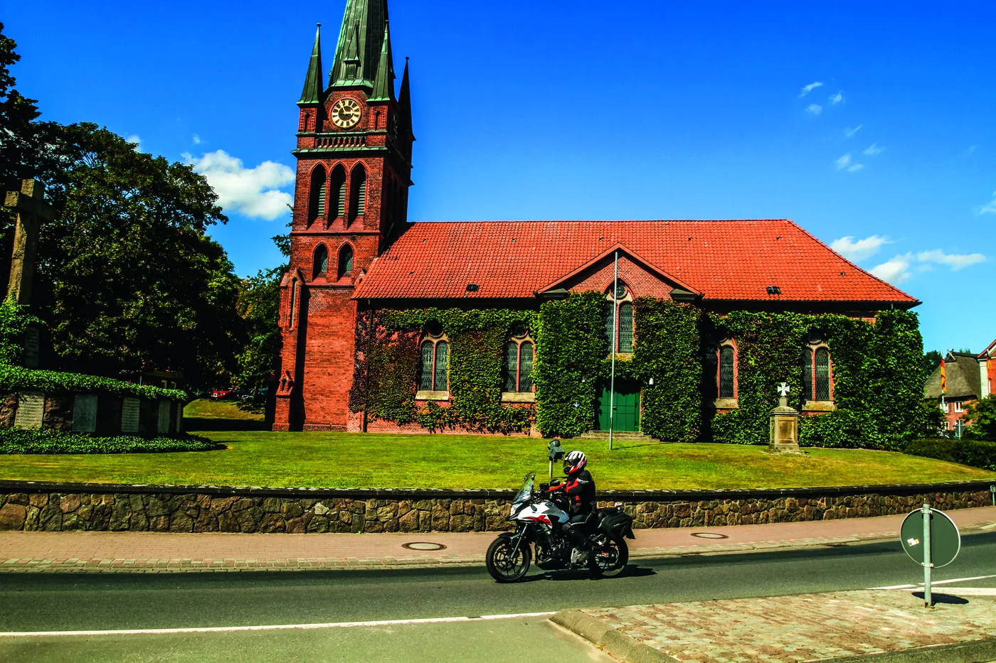 Backsteinkirche mit spitzem Turm, davor ein Motorrad Backsteinkirche mit spitzem Turm, davor ein Motorrad