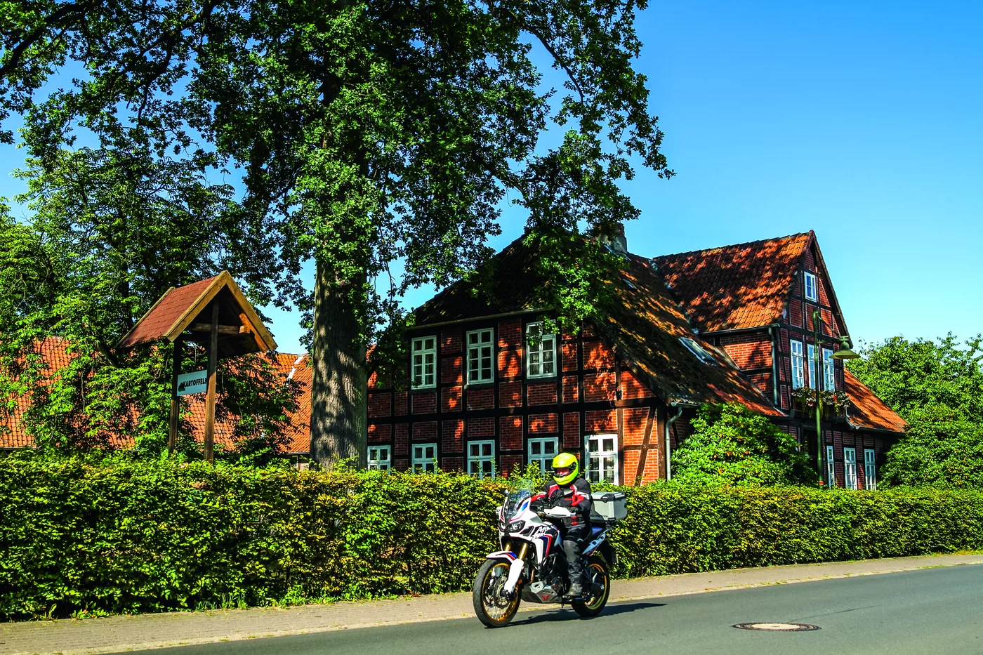 Motorrad vor einem großen Fachwerkhaus mit rotem Ziegeldach Motorrad vor einem großen Fachwerkhaus mit rotem Ziegeldach